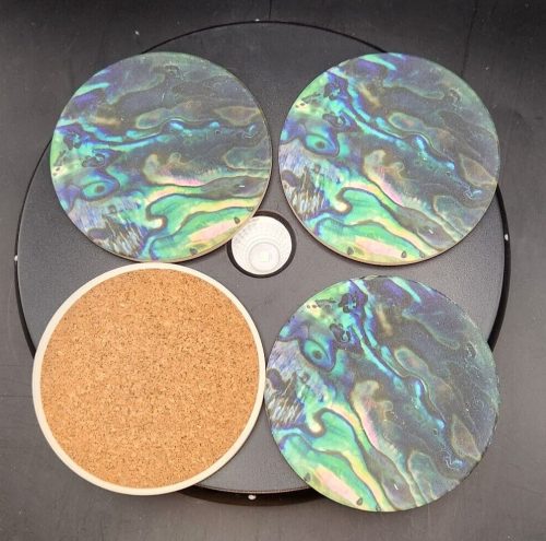 Set of four colorful abalone ceramic coasters with cork backing for protection.