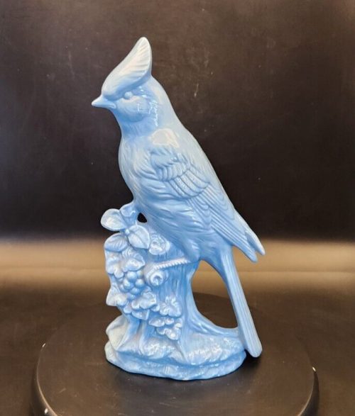 Signed ceramic blue jay bird figurine on a stump with flowers.