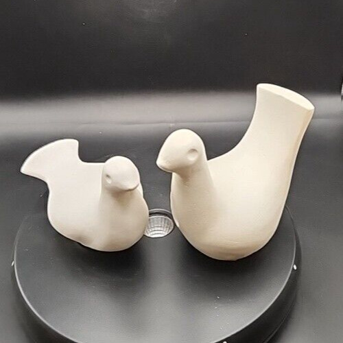 Two white ceramic homecoming birds for home décor or collectibles.