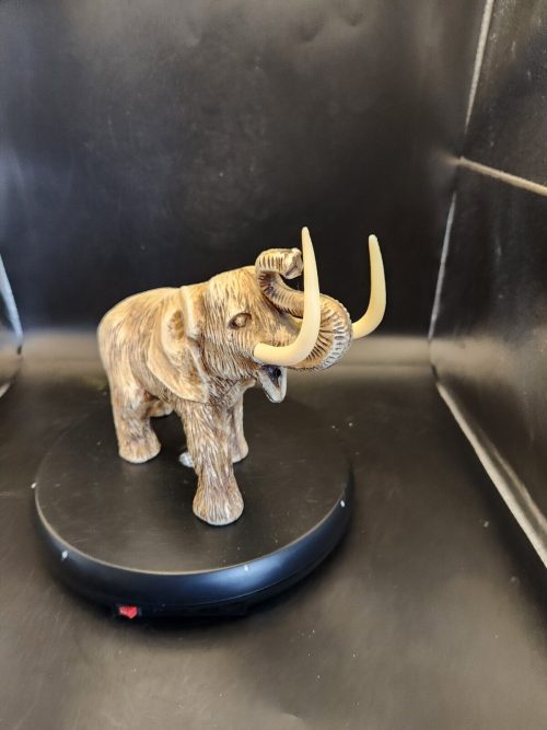 Vintage celluloid elephant statue with upturned tusks and intricate detailing.