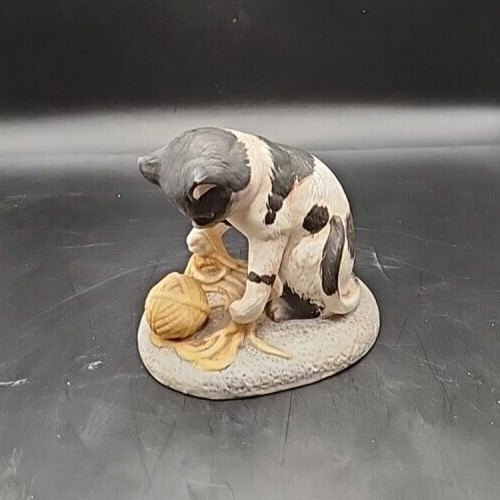 Cute kitten playing with colorful yarn figurine.