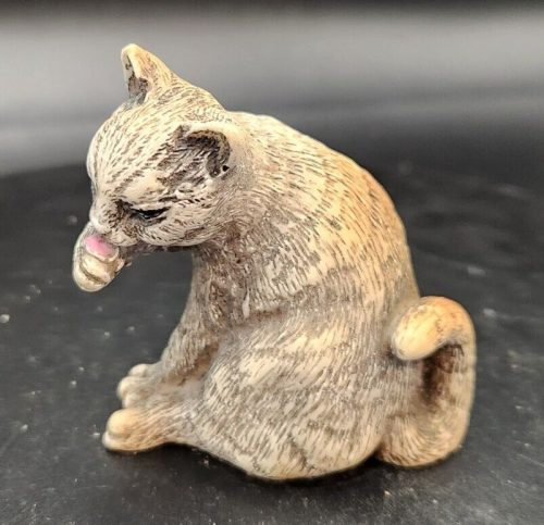 Artis Onia Rinke Nada cat figurine licking its paw for home decor.