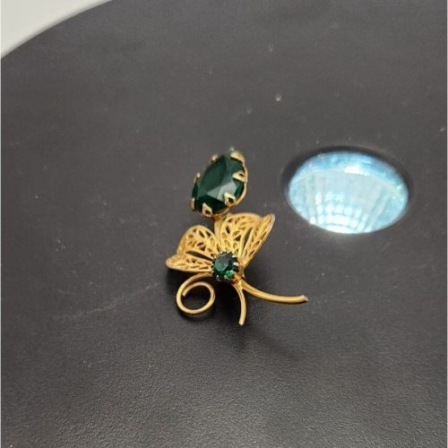 Vintage gold-tone flower brooch with emerald green rhinestones and prong setting.