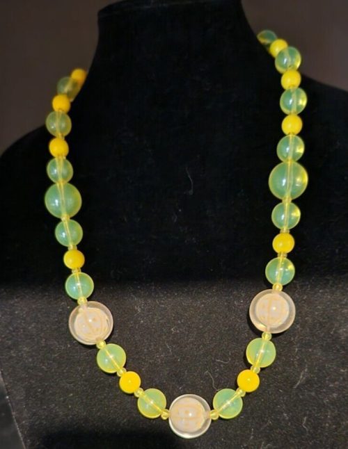 Vintage yellow beaded necklace glowing under UV light, 25.5 inches long.